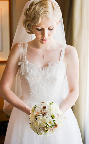 Bride with a fingerwave inspired hair looking down and holding a bouquet