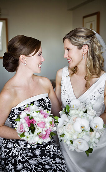 Bride and Bridesmaid smiling at each other while holding bouquet