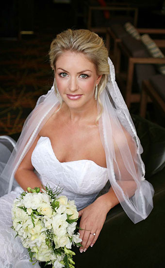 Blonde bride with a white rose bouquet smiling