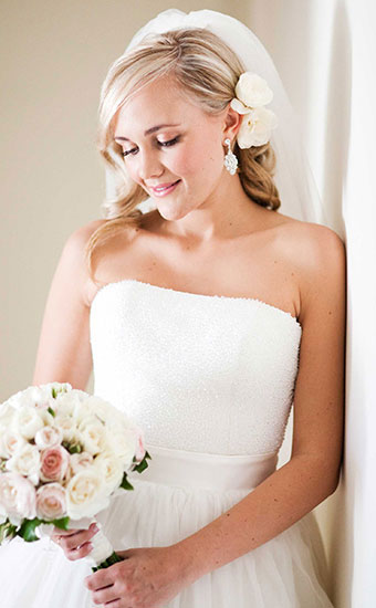 Bride with a blonde curly hairdos and white rose and veil